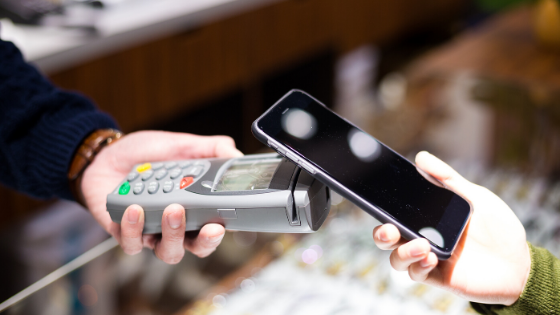 Person using mobile phone on pos machine