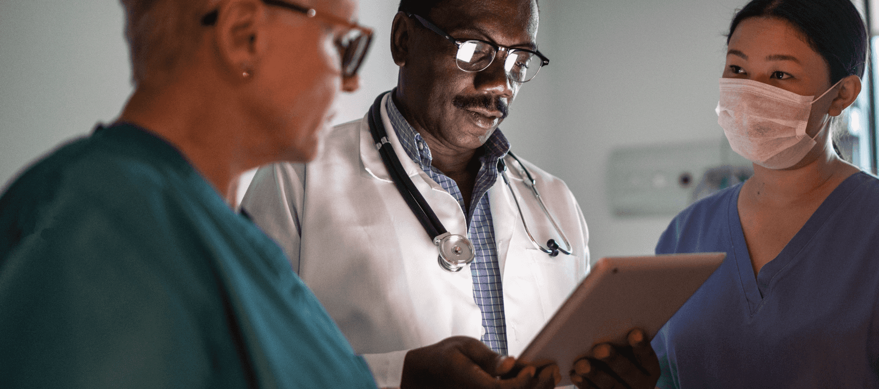 Three medical professionals looking at a tablet device